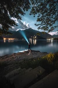 Man holding torch while standing at lakeshore during night