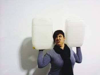 Portrait of young woman standing against white background