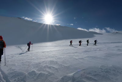 People on snowcapped mountain against sky