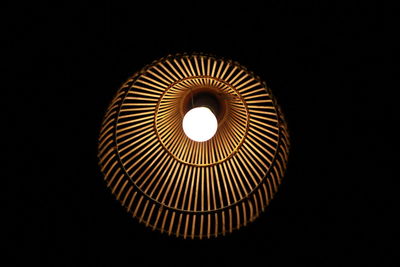Low angle view of illuminated lamp against black background