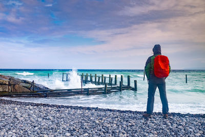 Man tourist watch how waves crash into wooden pier of fishing village vitt. ruegen island, germany.