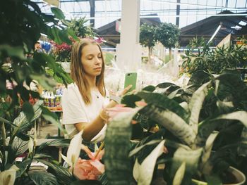 Beautiful young woman standing by flowering plants