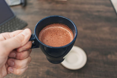 Midsection of person holding coffee cup on table