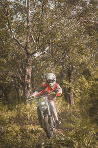 Man riding motorcycle against trees in forest