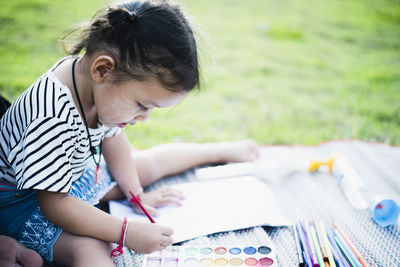 Side view of boy drawing on book at park