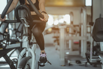 Low section of woman on exercise bike at gym