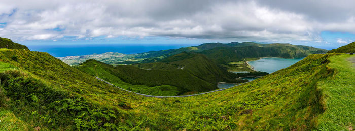 Panoramic view of green landscape and sea against sky