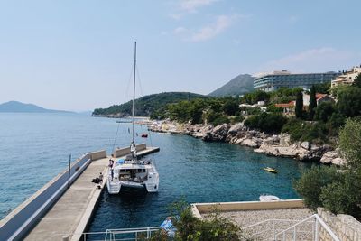 Sailboats on sea by city against sky