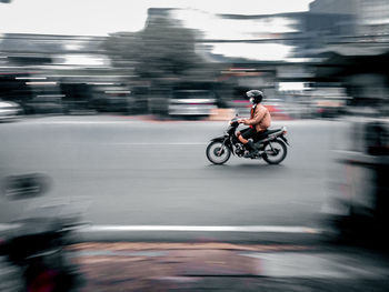 Side view of a man riding motorcycle on road