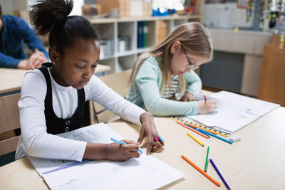 Schoolgirls studying at desk in classroom