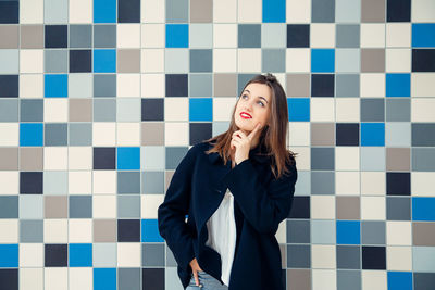 Beautiful young woman standing against tiled floor