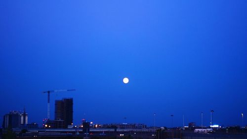 Full moon over cityscape at dusk