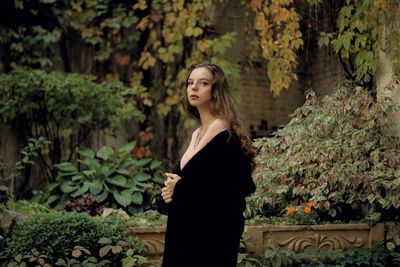 Portrait of young woman standing against plants