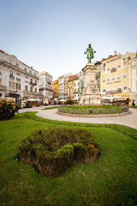 Statue by buildings against sky in city