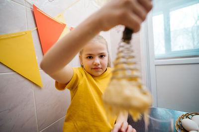 Girl kneads the dough for the easter holiday, white eggs on the table, burning candles