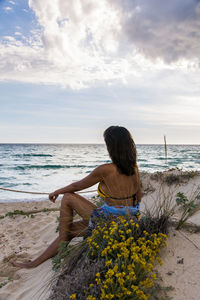 Rear view of woman sitting on beach