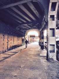 Rear view of man walking in illuminated corridor