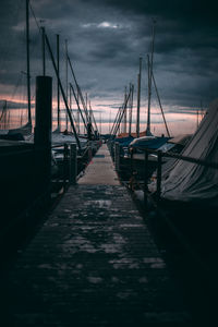 Sailboats moored in marina at sunset