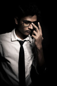 Young man wearing eyeglasses against black background