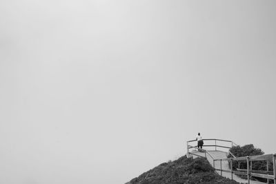 Low angle view of man standing on mountain against sky