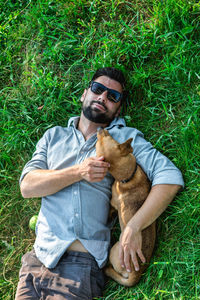 Top view of man and dog lying on green grass. attractive european man is hugging his dog.