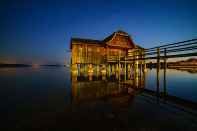 Pier over lake against sky at night