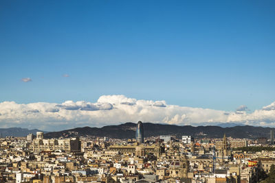 Distant view of torre agbar in city against sky