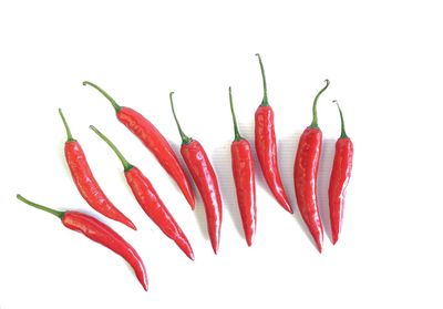 Close-up of red chili peppers against white background