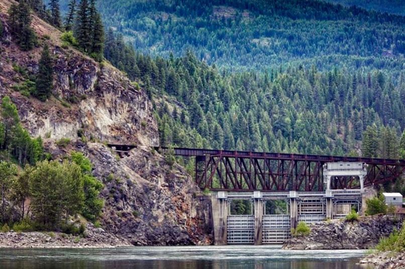 tree, water, built structure, architecture, mountain, tranquility, railing, tranquil scene, plant, nature, river, beauty in nature, growth, forest, scenics, lake, rock - object, day, connection, house