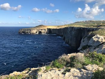 Scenic view of sea by cliff against sky