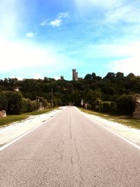 Road by trees against sky in city