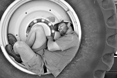 Side view of man sleeping on tire