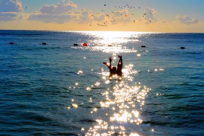 Silhouette male friends in sea during sunset