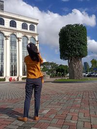 Rear view of woman standing on footpath against sky