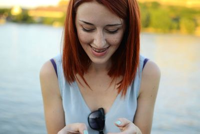 Close-up of smiling woman against lake