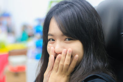 Close-up portrait of young woman smiling while sitting on chair