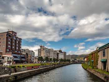 River amidst houses and buildings against sky