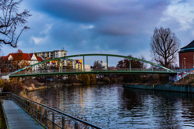 Bridge over river in city against sky