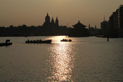 Silhouette of boats in water at sunset