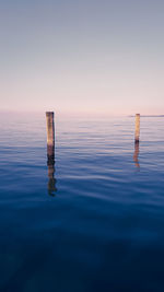 Scenic view of wooden post in sea against sky