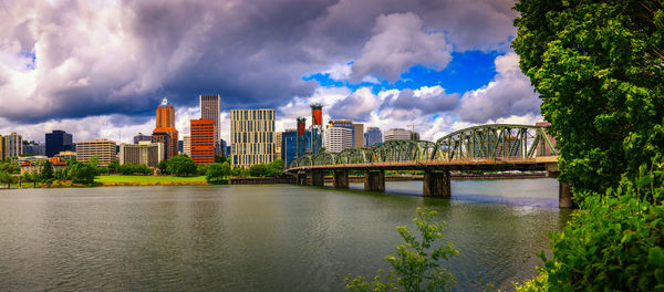 Buildings by river against cloudy sky