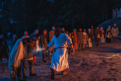 Group of people in traditional clothing during festival at night