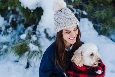 Portrait of woman with dog in snow