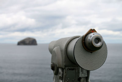 Close-up of coin-operated binoculars by sea against sky