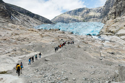 Group of people walking on landscape against mountain range