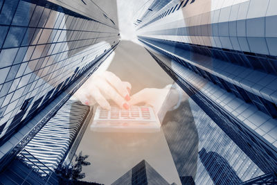 Digital composite image of hand holding glass building against sky