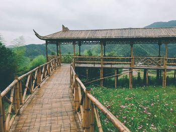 Footbridge over lake against sky