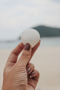 Close-up of hand holding ring over sea against sky