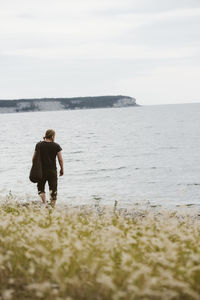 Young man walking on beach, gotland, sweden