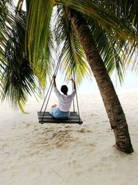 Rear view of man sitting on chair at beach